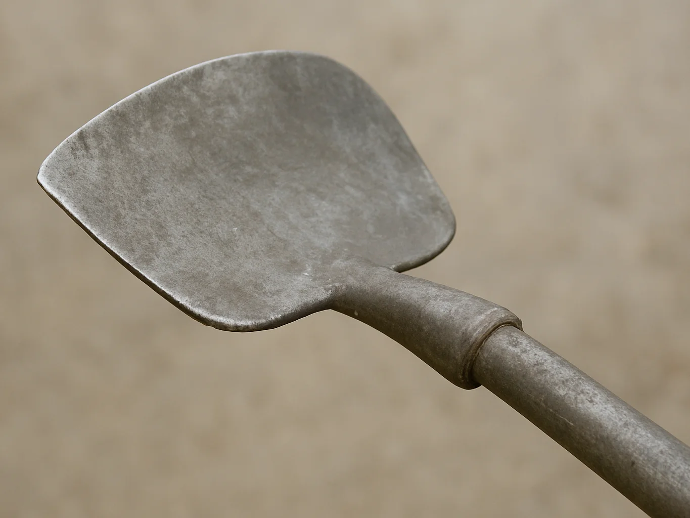 Close detail of a metal garden hoe head with a smooth fabricated edge, soft neutral daylight, clean documentary mood, 50